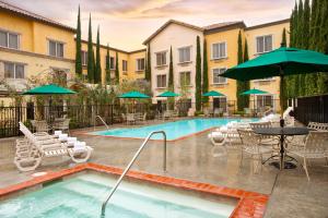 a pool with chairs and tables and umbrellas at Ayres Hotel Laguna Woods - Aliso Viejo in Laguna Woods