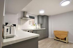 a kitchen with gray cabinets and a white counter top at Pebbles in Lyme Regis