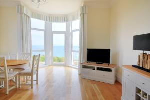 een woonkamer met een televisie en een tafel met stoelen bij Ocean View in Seaton