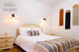 a bedroom with a white bed with a striped blanket on it at Hotel Rural SAN REMO in Santa Rosa de Cabal