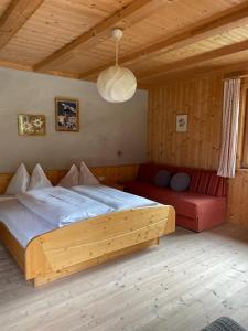 a bedroom with a large bed and a red couch at Edelweißhütte in Funes