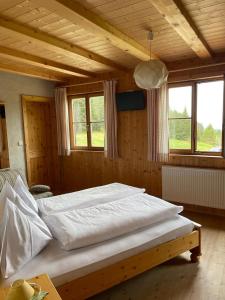 a large bed in a wooden room with windows at Edelweißhütte in Funes