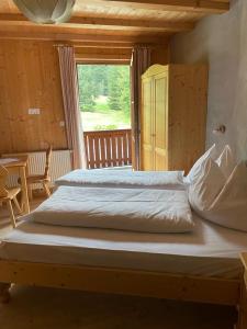 Cama grande en habitación con ventana en Edelweißhütte en Funes