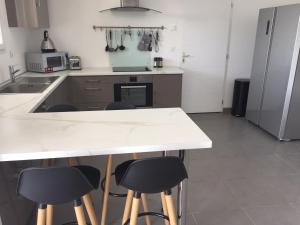 eine Küche mit einer weißen Theke und Stühlen in der Unterkunft Villa privative 3 chambres et piscine priv près Carcassonne in Carcassonne