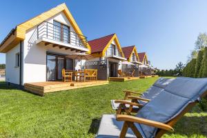 a house with a lawn with a couple of lounge chairs at Domki wakacyjne 4 YOU in Ustka