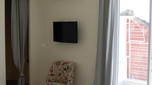 a tv on a wall with a chair next to a window at Le 2 Baie di Sestri Levante in Sestri Levante