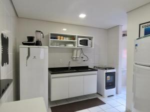 a kitchen with white cabinets and a refrigerator at UBAtubah HOMES 23A 100m Praia Grande WIFI piscina in Ubatuba