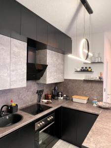 a kitchen with black cabinets and a sink at Guest House Eden in Bihać