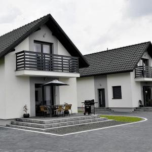 een wit huis met een terras met een tafel en stoelen bij Domki na Krótkiej in Spytkowice