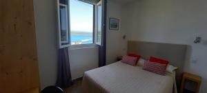 a bedroom with a bed with a large window at Hôtel du Golfe in Bonifacio