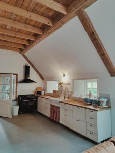 una grande cucina con armadi bianchi e soffitti in legno di B & B Wijdzicht a Wolsum