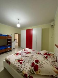 a bedroom with a bed with a red and white comforter at Alexa Beach Apartment in Velipojë