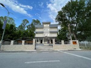 a white building with a fence in front of a street at Alexa Beach Apartment in Velipojë