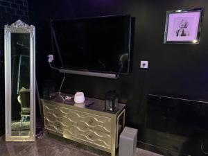 telewizor z płaskim ekranem stojący na komodzie z lustrem w obiekcie La Suite Marylin, Loft de 90m2 avec Sauna et Jacuzzi w mieście Riom