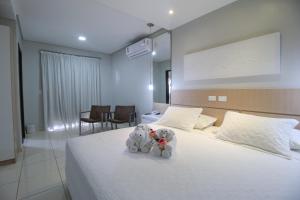 two stuffed animals sitting on a bed in a bedroom at Marruá Hotel in Bonito