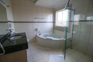 a bathroom with a tub and a sink and a shower at Marruá Hotel in Bonito