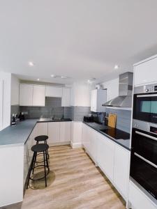 una cocina con armarios blancos y taburete. en Prosper House Apartment 2 en Norwich