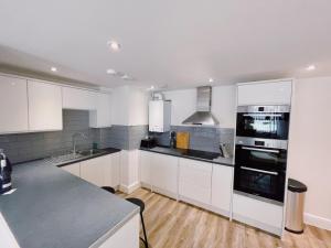 a kitchen with white cabinets and a counter top at Prosper House Apartment 2 in Norwich +8 photos