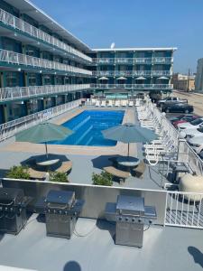 a large building with a pool and tables and umbrellas at Royal Canadian Motel in Wildwood