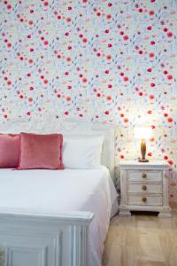 1 dormitorio con cama blanca y papel pintado con motivos florales en B&B Calamoresca, en Àrbatax