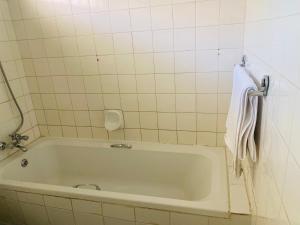 a bath tub in a tiled bathroom with a towel at Lancy Apartments in Gaborone +16 photos