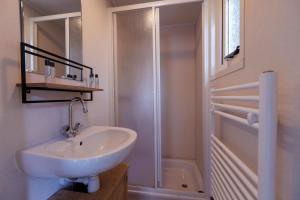 a white bathroom with a sink and a shower at Kek huisje aan de Maas in Andel +19 photos