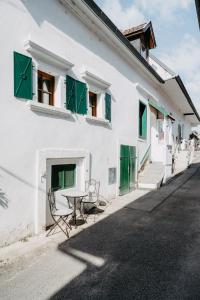 メルビッシュ・アム・ゼーにあるFerienhaus in historischer Hofgasseの白い建物(緑のシャッター付き窓、テーブル付)
