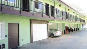 a car parked next to a building with a white garage at Eagle Rock Motel in Los Angeles