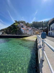 a man standing on a fence looking at the water at El Maltés in Cudillero