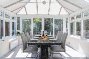 a conservatory dining room with a table and chairs at Sea La Vie in Carbis Bay