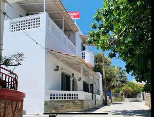 a white building with a balcony on a street at Semiramis Guesthouse in Adamas