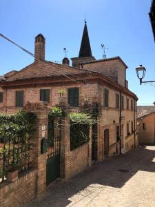 stary ceglany budynek z wieżą zegarową na górze w obiekcie Casa Rosy nel centro del borgo di Patrignone w mieście Patrignone