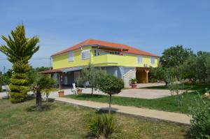 une maison jaune avec un toit rouge dans l'établissement Studio Apartments Luka Biograd - Benkovac, à Benkovac