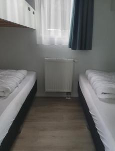 two beds in a room with a window and a radiator at Klein Ramdal in Putten