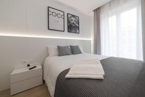 a white bedroom with a bed with a towel on it at Apartamento Logroño Plaza Ayuntamiento in Logroño