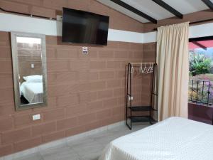 ein Schlafzimmer mit einem TV an einer Backsteinwand in der Unterkunft CASA FINCA RANCHO APPALOOSA Vereda TIERRA LINDA Finca # 3 in Urrao