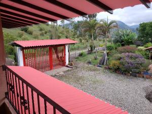 einen Balkon mit einem roten Dach und einem Garten in der Unterkunft CASA FINCA RANCHO APPALOOSA Vereda TIERRA LINDA Finca # 3 in Urrao