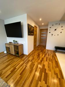 a living room with a flat screen tv and wooden floors at Siguldas apartment in Liepāja