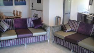 a living room with two couches and a kitchen at Undercliff Guest House in Trinity