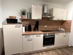 a kitchen with white cabinets and a sink at Ferienwohnung Auersbergblick in Schönheide