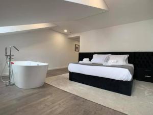 um quarto com uma cama grande e uma banheira em PALHOTAS GUEST HOUSE - Suite Premium Bom Jesus em Braga