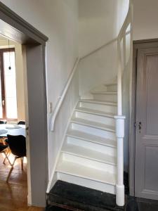 Una escalera blanca en una habitación con puerta en Huis Louis, en Kortessem