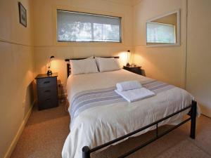 a bedroom with a large bed with two windows at Noonameena Cottage in Halls Gap