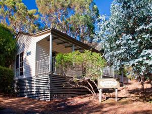 une petite maison avec un panneau devant dans l'établissement Noonameena Cottage, à Halls Gap