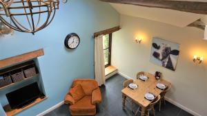 een woonkamer met een houten tafel en een klok bij Sheep Dip Cottage - 5* Cyfie Farm, with log burner and private hot tub in Llanfyllin