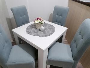 un tavolo bianco con due sedie e un vaso con fiori di VEMIUR a Čačak