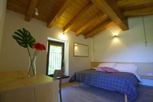 een slaapkamer met een bed en een vaas met een bloem bij Péstrofa in San Pietro al Natisone
