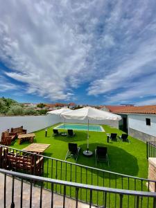 un patio con ombrellone e sedie bianchi e prato di Complejo Rural Rincón del Paraíso a Valencia del Mombuey