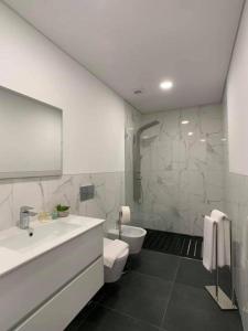 een witte badkamer met een wastafel en een toilet bij PALHOTAS GUEST HOUSE - Apartamento Palhotas in Braga