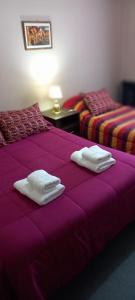 two beds in a room with purple sheets and towels at My House in El Calafate in El Calafate